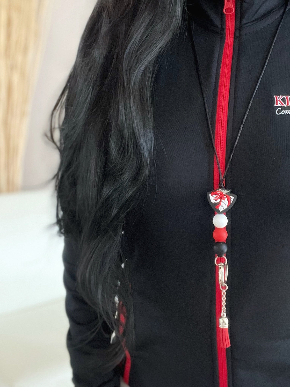 Close Up of woman with long black hair wearing a dragon lanyard with a red tassel and black, red, and white silicone beads
