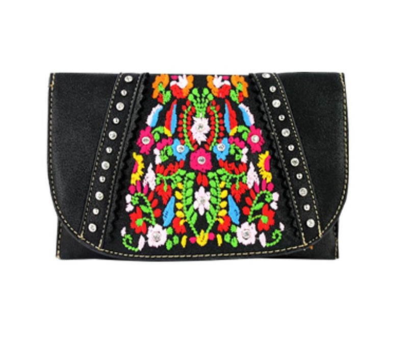 The image shows a black "American Bling" clutch crossbody shoulder handbag by Montana West. The bag features a colorful, embroidered floral design on the front flap, accented with silver studs along the edges. The brand "Montana West" is associated with Western-style handbags known for their blend of traditional and contemporary design elements. The "American Bling" line specifically incorporates eye-catching embellishments. Crossbody bags are designed to be worn across the body, offering both style and pra