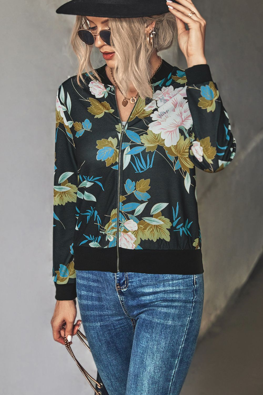 Woman wearing a black floral zip up lightweight floral bomber jacket with jeans